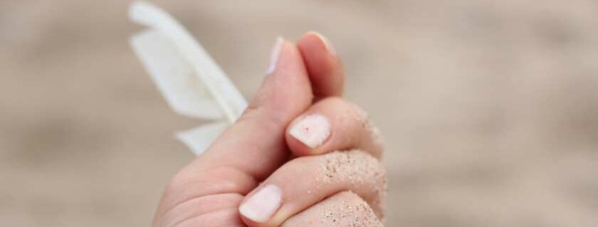 hand holding a white feather and white feather meaning in the bible