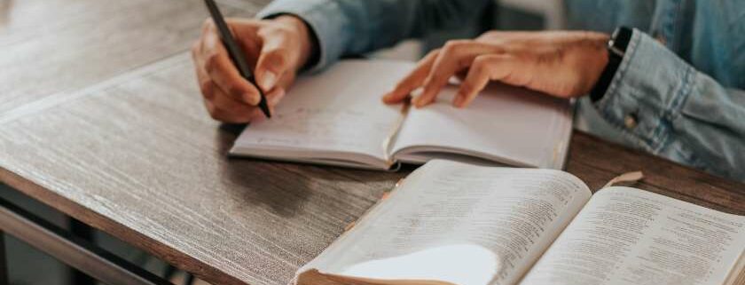 man writing on notebook with a bible and 333 meaning bible