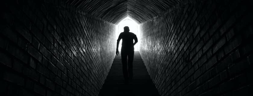 silhoutte of man light at the end of the tunnel