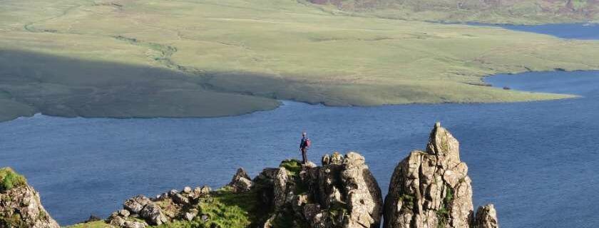 man standing on a high rock formation over sea and difference between faith and trust