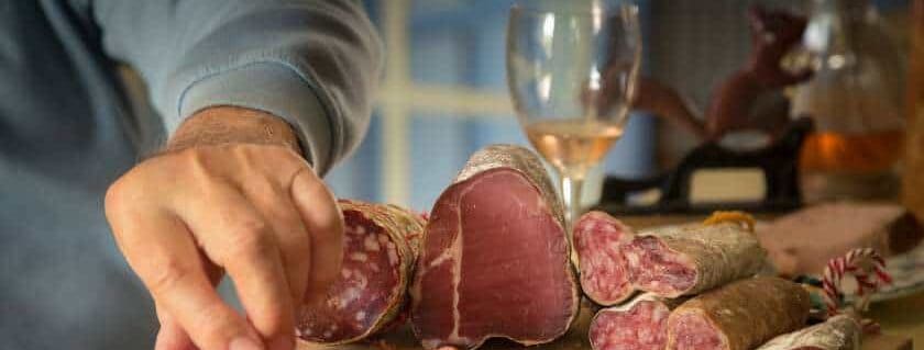 dried meat and glass of wine on wooden cutting board
